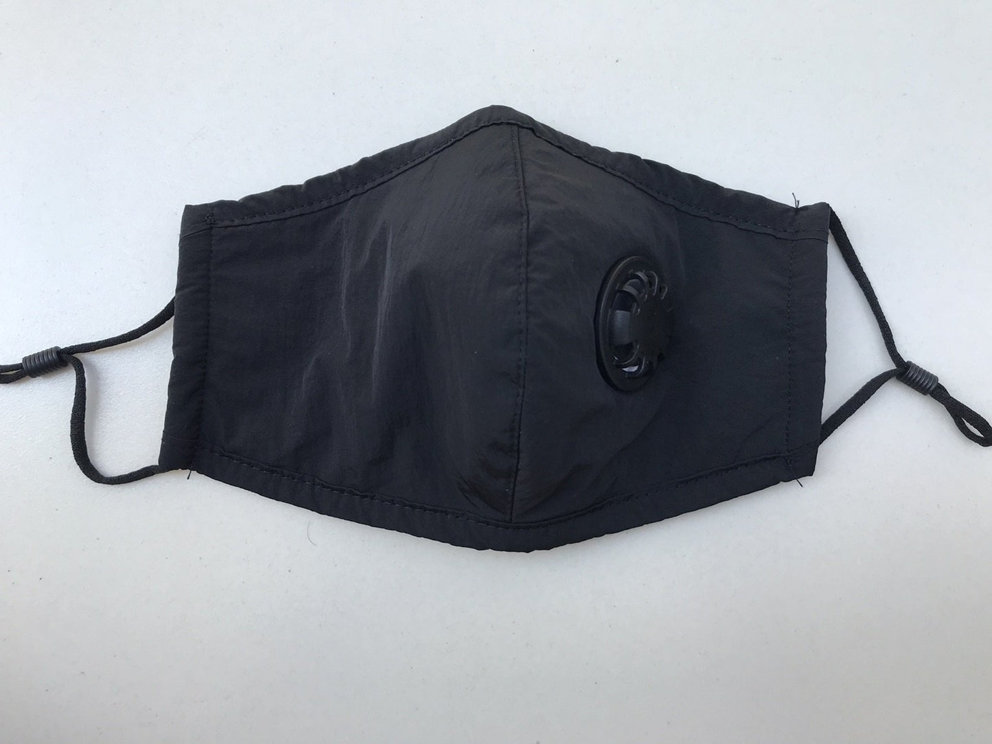 Black reusable adult face mask with adjustable straps and breathing valve, 3-ply, designed for health and safety.