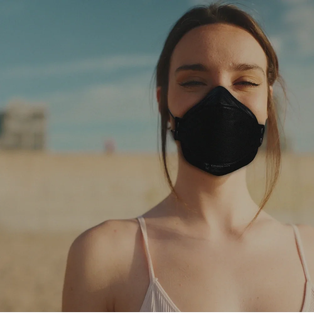 Woman smiling wearing a black Hlpmedical Trident Project 3 FFP3 respirator mask for respiratory protection.