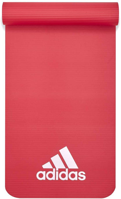 Red Adidas fitness mat 7mm for yoga, pilates, judo, and exercise training, shown rolled out on gym floor.